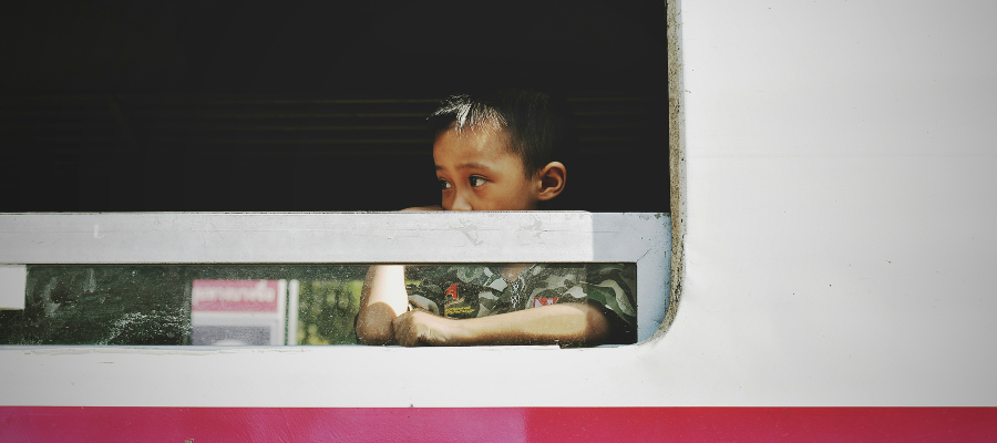 Jeune enfant regardant par la fenêtre d'un train en Thaïlande